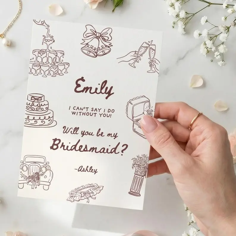Bridesmaid proposal card in cream with brown line-drawn champagne tower, wedding bells, cake, ring box, vintage car, and bouquet motifs framing the words Will You Be My Bridesmaid